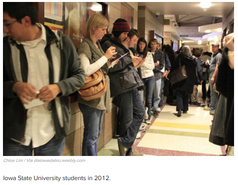 Students on their phones in hallway waiting for class
